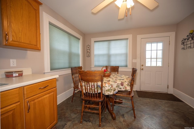 dining area featuring ceiling fan and dark tile patterned flooring