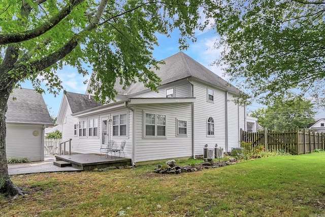 rear view of house with a lawn, central AC, and a deck