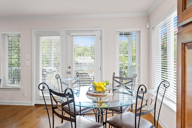 dining space with a wealth of natural light, crown molding, hardwood / wood-style floors, and french doors