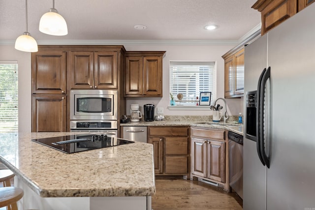 kitchen featuring stainless steel appliances, hardwood / wood-style floors, ornamental molding, and light stone countertops