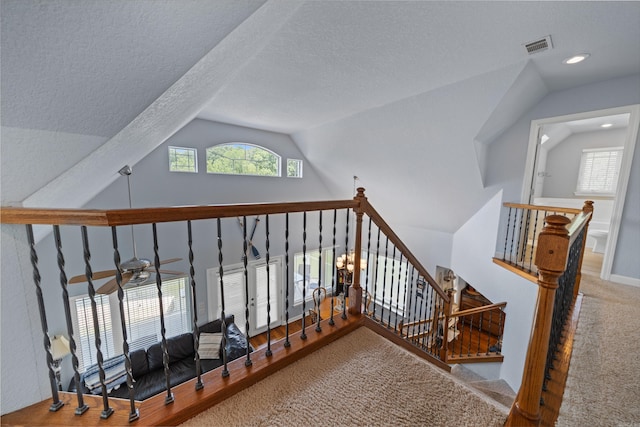 stairs with carpet, vaulted ceiling, a textured ceiling, and ceiling fan