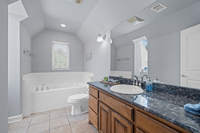 bathroom featuring vaulted ceiling, vanity, tile patterned floors, toilet, and a bathtub