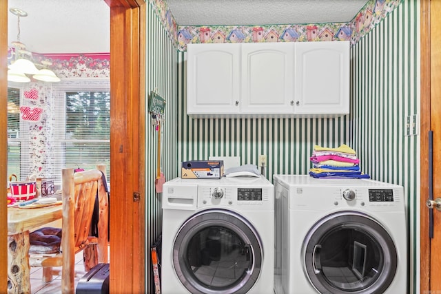 washroom featuring independent washer and dryer, a textured ceiling, and cabinets