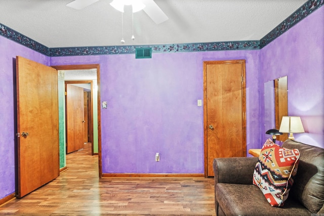 sitting room featuring ceiling fan, a textured ceiling, and wood-type flooring