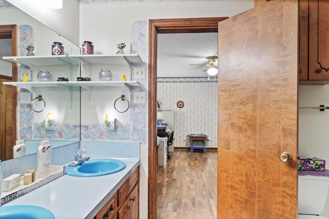 bathroom featuring ceiling fan, toilet, vanity, hardwood / wood-style floors, and a textured ceiling