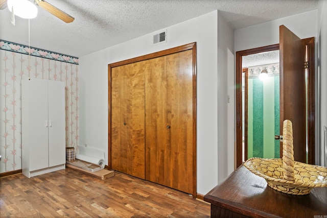 unfurnished bedroom with hardwood / wood-style floors, a textured ceiling, and ceiling fan