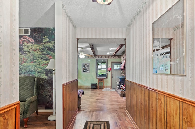 hallway with a textured ceiling, beam ceiling, and wood-type flooring