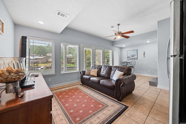 tiled living room with ceiling fan, a healthy amount of sunlight, and a textured ceiling