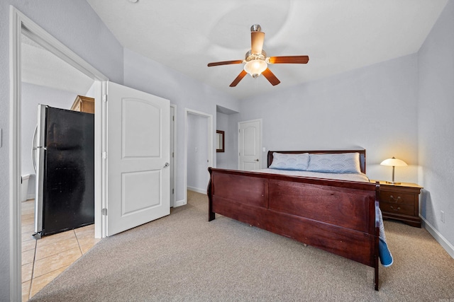 bedroom with ceiling fan, light colored carpet, and stainless steel fridge