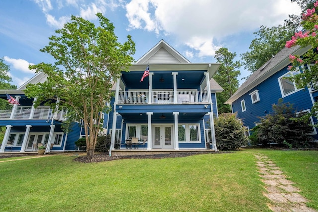 rear view of house featuring french doors, ceiling fan, a lawn, and a balcony