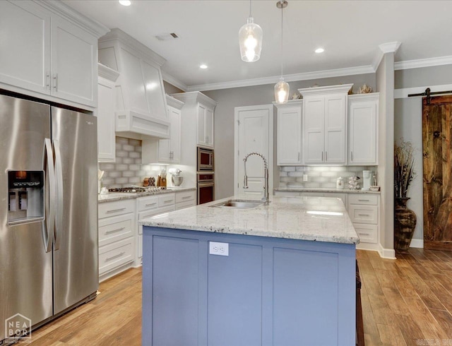 kitchen with a barn door, stainless steel appliances, sink, and tasteful backsplash