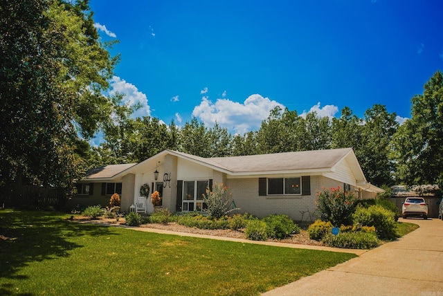 ranch-style house with brick siding, concrete driveway, a front lawn, and fence