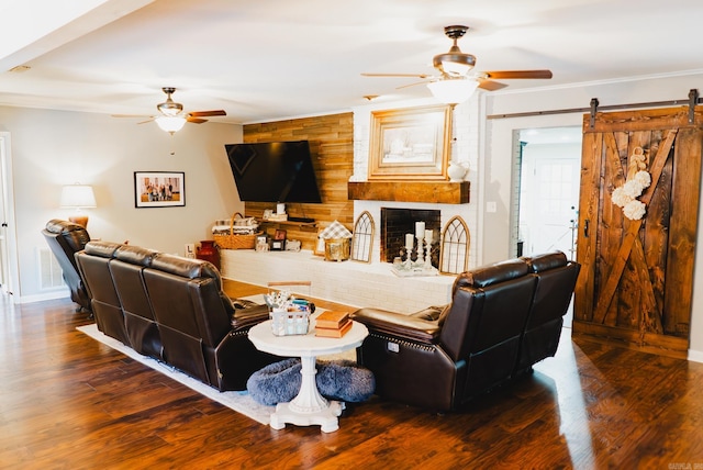 living room with wood walls, ceiling fan, hardwood / wood-style flooring, and a barn door