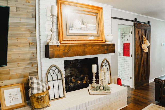 details featuring a fireplace, a barn door, wood-type flooring, and crown molding