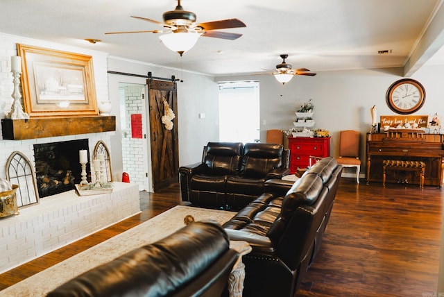 living room with ceiling fan, dark wood-type flooring, brick wall, a barn door, and crown molding