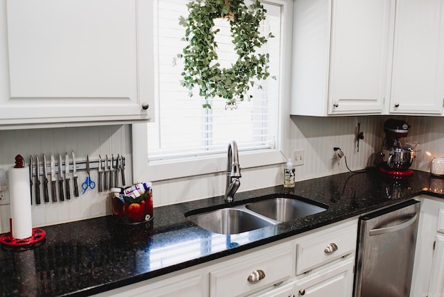 kitchen with a sink, white cabinetry, dark stone counters, and stainless steel dishwasher