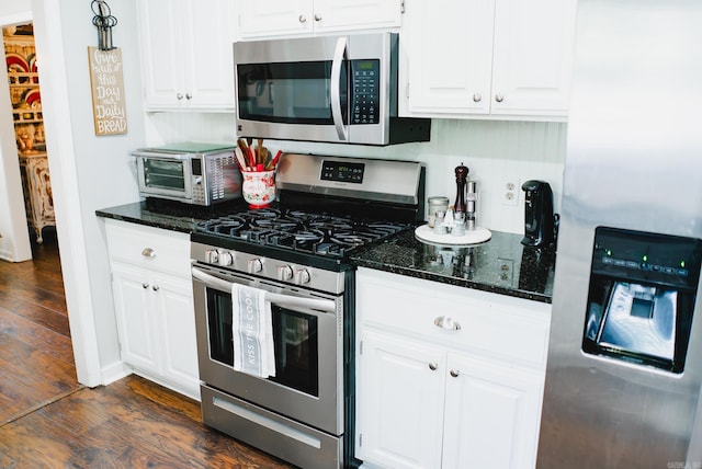 kitchen featuring white cabinetry, appliances with stainless steel finishes, dark wood-type flooring, and dark stone counters