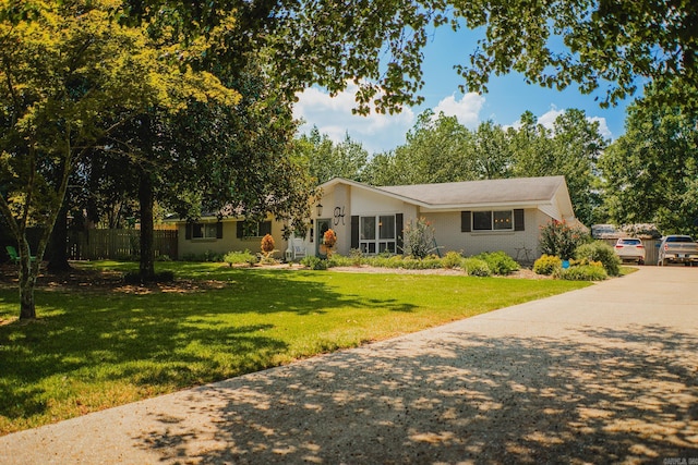 ranch-style house featuring concrete driveway, a front lawn, and fence