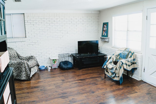 living room featuring brick wall, crown molding, and dark hardwood / wood-style flooring