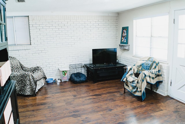 interior space with visible vents, brick wall, wood finished floors, and crown molding