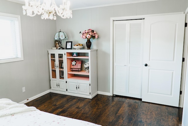 bedroom with a closet, crown molding, hardwood / wood-style floors, and an inviting chandelier