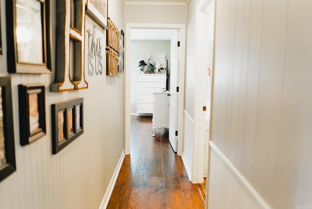 hallway with dark wood-type flooring, crown molding, and baseboards