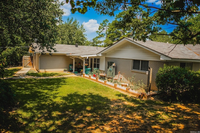 back of house featuring brick siding, a lawn, and a gate