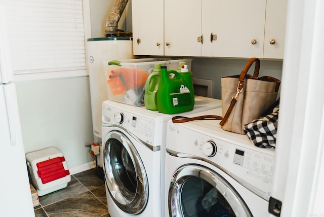 laundry room with dark tile patterned flooring, separate washer and dryer, cabinets, and electric water heater