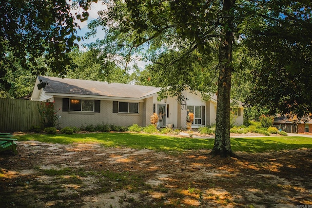 single story home featuring brick siding, a front lawn, and fence