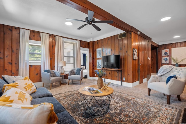 living room with wood walls, ceiling fan, and carpet