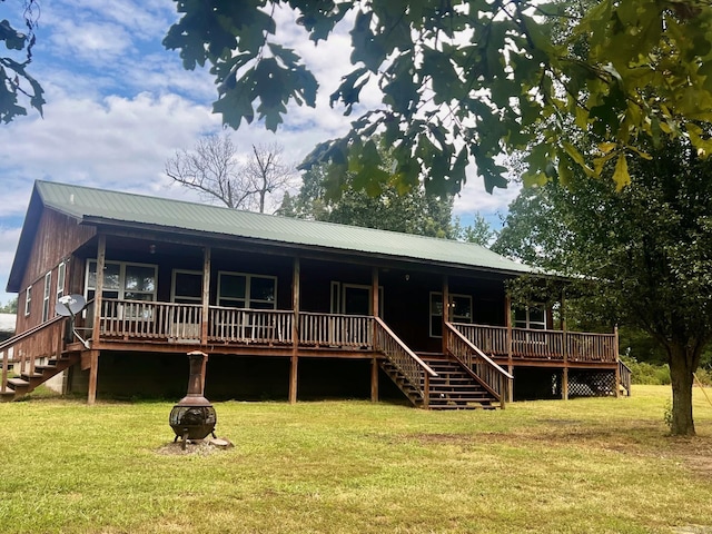 rear view of property featuring a lawn, a fire pit, and stairs