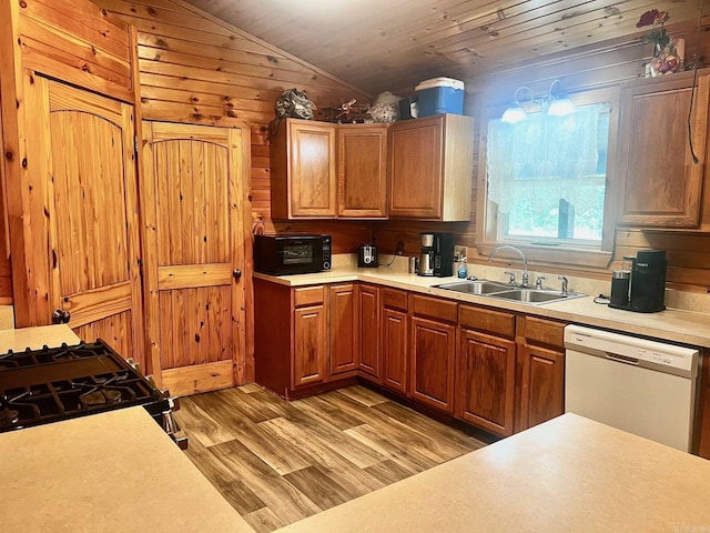 kitchen featuring sink, light wood-type flooring, wooden walls, lofted ceiling, and white dishwasher