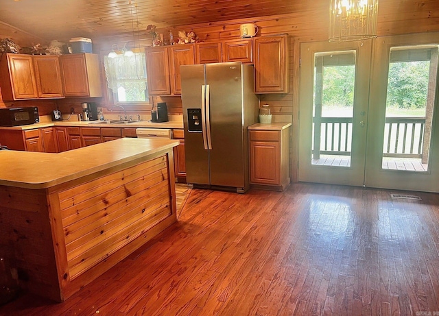 kitchen featuring light wood-type flooring, stainless steel fridge, sink, and wood walls