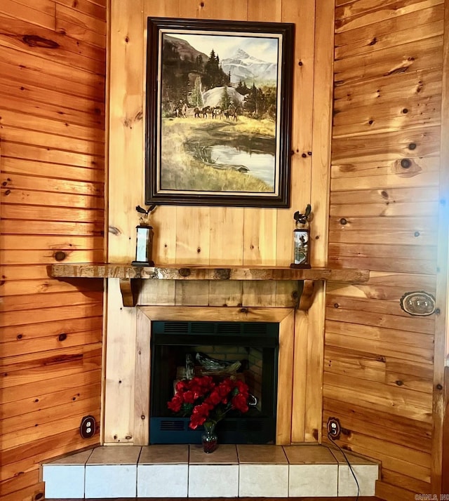 details with a tiled fireplace and wooden walls