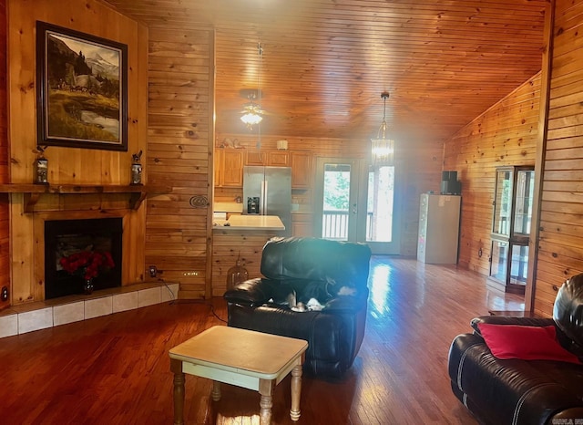 living room with lofted ceiling, wooden walls, a fireplace, wood finished floors, and wood ceiling