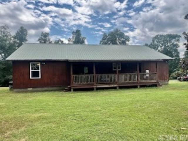 rear view of house featuring a wooden deck and a yard