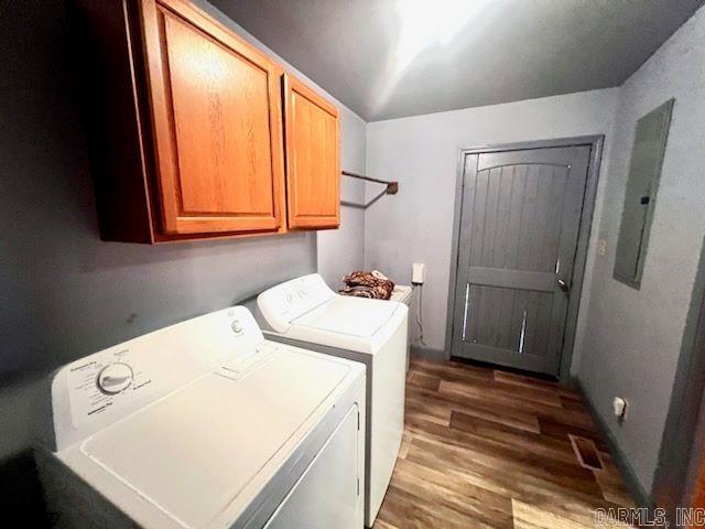 laundry area with separate washer and dryer, electric panel, wood-type flooring, and cabinets