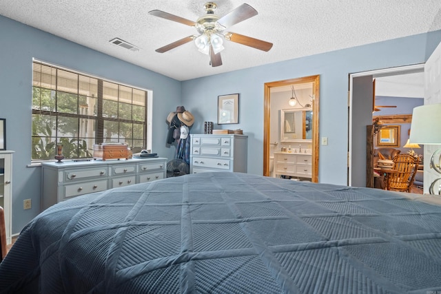 bedroom with ceiling fan, a textured ceiling, and ensuite bath