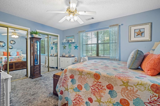 bedroom featuring ceiling fan, light carpet, two closets, and a textured ceiling