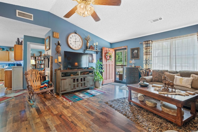 living room featuring a textured ceiling, ceiling fan, vaulted ceiling, and dark wood-type flooring