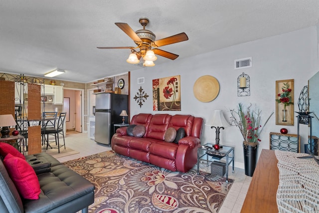 living room featuring ceiling fan, a textured ceiling, and light tile patterned flooring