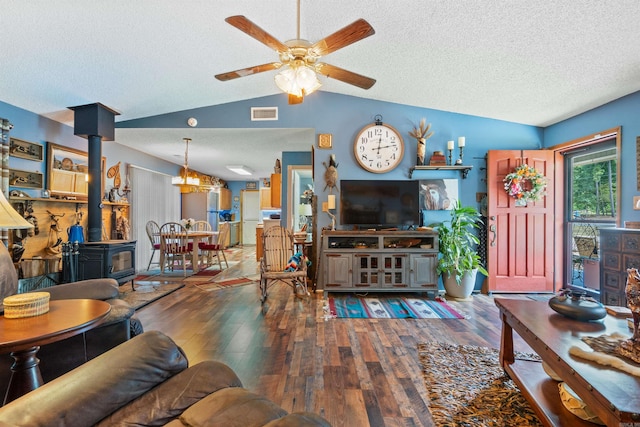 living room with a wood stove, a textured ceiling, lofted ceiling, ceiling fan with notable chandelier, and hardwood / wood-style flooring