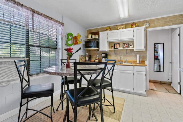 kitchen featuring a textured ceiling, white cabinets, light tile patterned floors, and sink