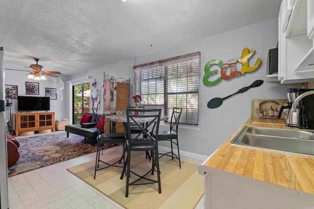 kitchen featuring sink, light tile patterned floors, a textured ceiling, ceiling fan, and white cabinets