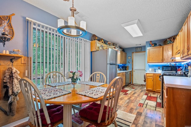 dining space with a notable chandelier, a textured ceiling, and light hardwood / wood-style floors