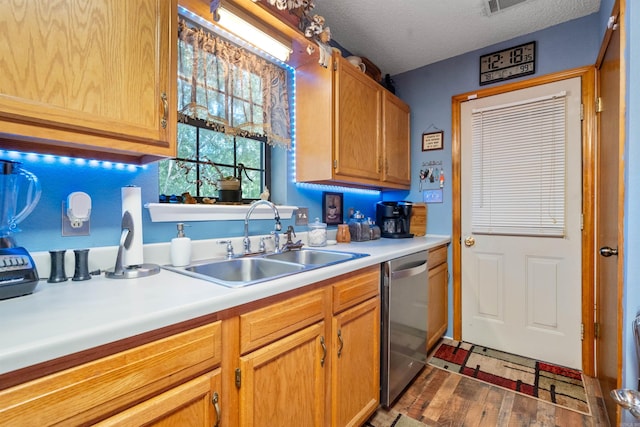 kitchen featuring sink, hardwood / wood-style floors, stainless steel dishwasher, and a textured ceiling