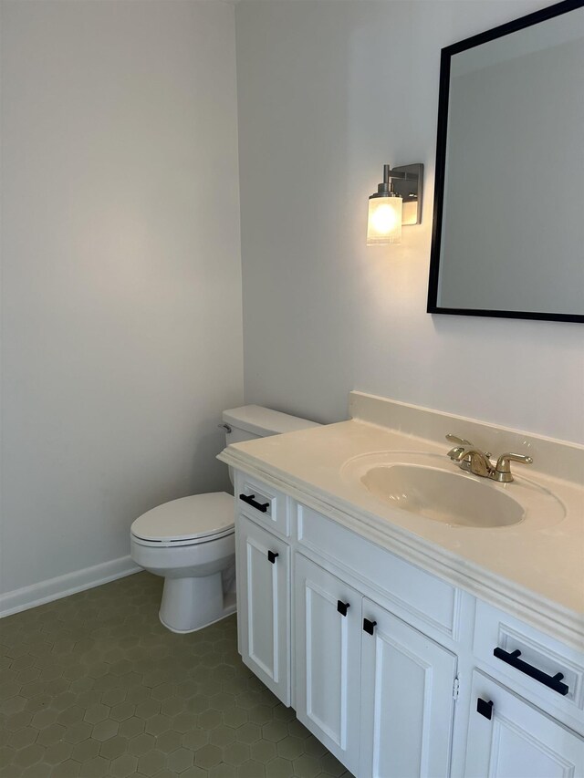 bathroom with toilet, vanity, and tile patterned floors