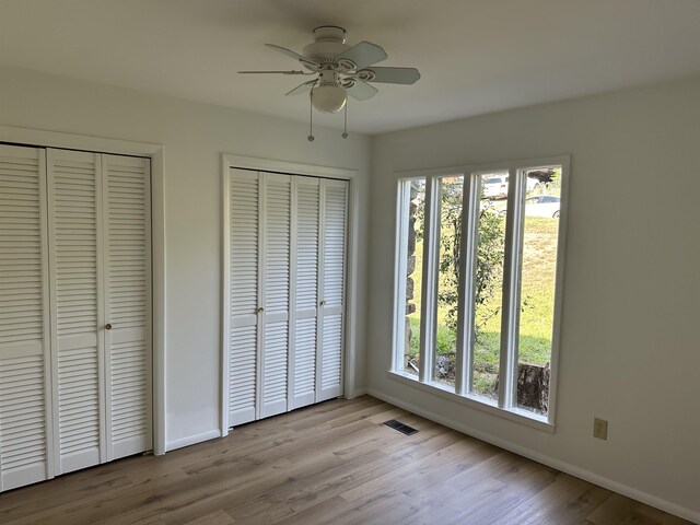 unfurnished bedroom with light hardwood / wood-style floors, multiple closets, and multiple windows