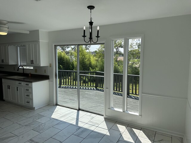 interior space with light tile patterned floors, ceiling fan with notable chandelier, sink, and a healthy amount of sunlight