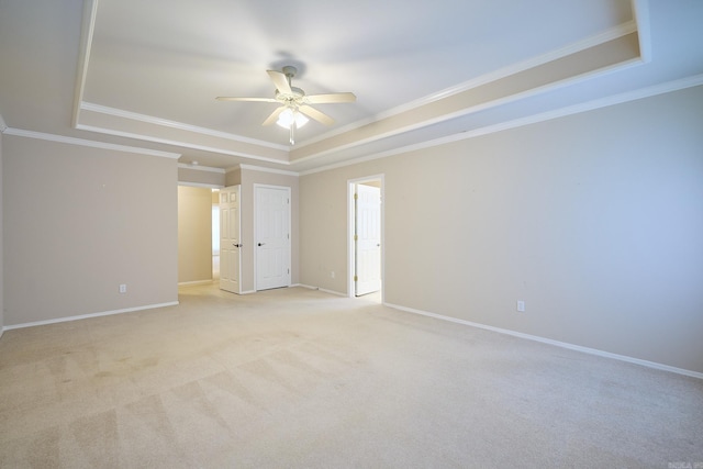 spare room with ceiling fan, light colored carpet, crown molding, and a tray ceiling